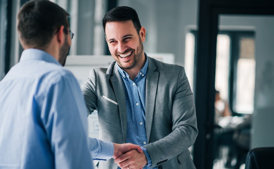 Hombres pasándose la mano en una oficina corporativa